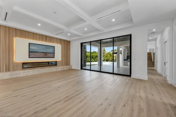 Unfurnished living room with coffered ceiling, beam ceiling, and light hardwood / wood-style floors
