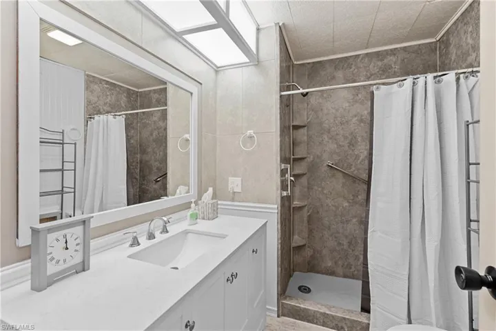 Full bathroom featuring a tile shower, vanity, and ornamental molding