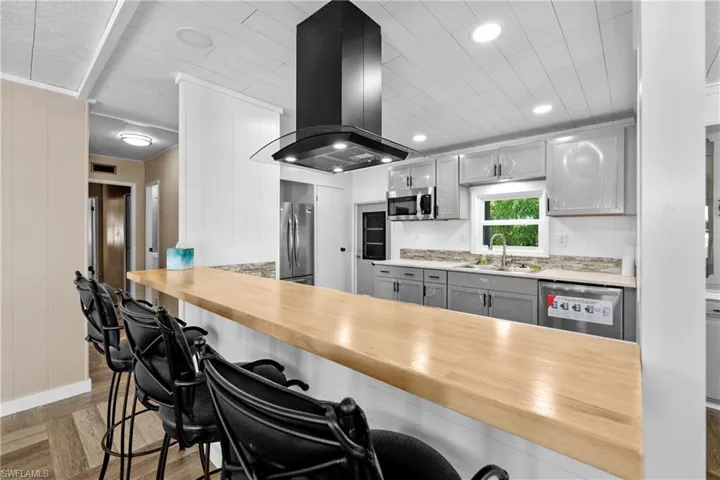 Kitchen featuring appliances with stainless steel finishes, island range hood, a sink, gray cabinets, and recessed lighting