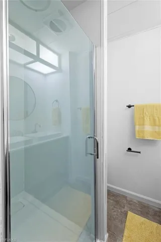 Bathroom featuring a shower stall, wood finished floors, and baseboards