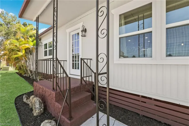 View of exterior entry with a porch, a lawn, and radiator heating unit