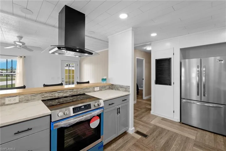 Kitchen featuring stainless steel appliances, island exhaust hood, healthy amount of natural light, gray cabinetry, and recessed lighting