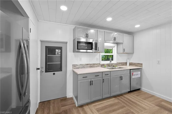 Kitchen with stainless steel appliances, a sink, gray cabinetry, light countertops, and recessed lighting