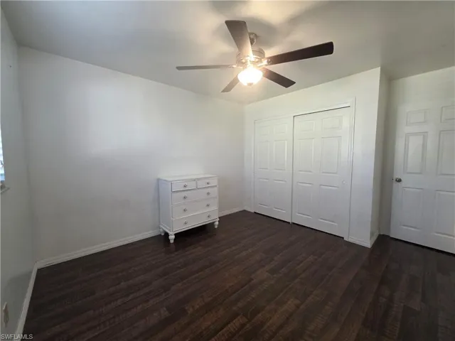 Unfurnished bedroom with a closet, dark wood-style flooring, and ceiling fan