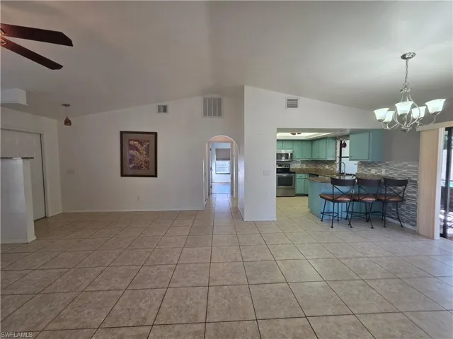 Kitchen with pendant lighting, lofted ceiling, a breakfast bar area, a chandelier, and arched walkways