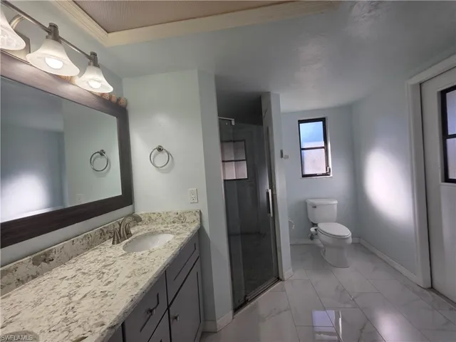 Full bathroom featuring vanity, a shower stall, light marble finish floors, and ornamental molding