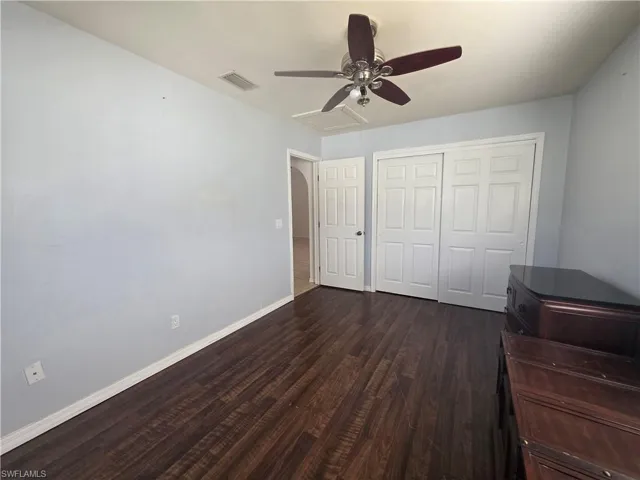 Unfurnished bedroom featuring ceiling fan, a closet, and dark wood-style flooring