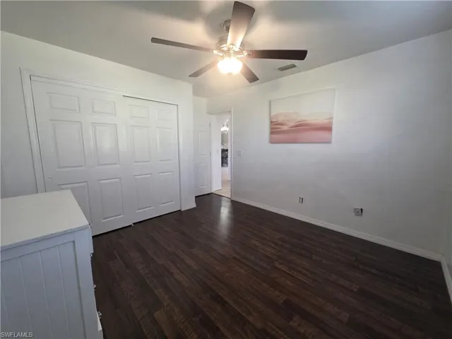 Unfurnished bedroom featuring a closet, ceiling fan, and dark wood-style floors