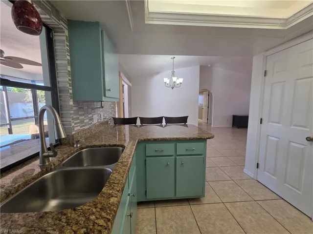 Kitchen featuring green cabinets, arched walkways, a peninsula, and pendant lighting