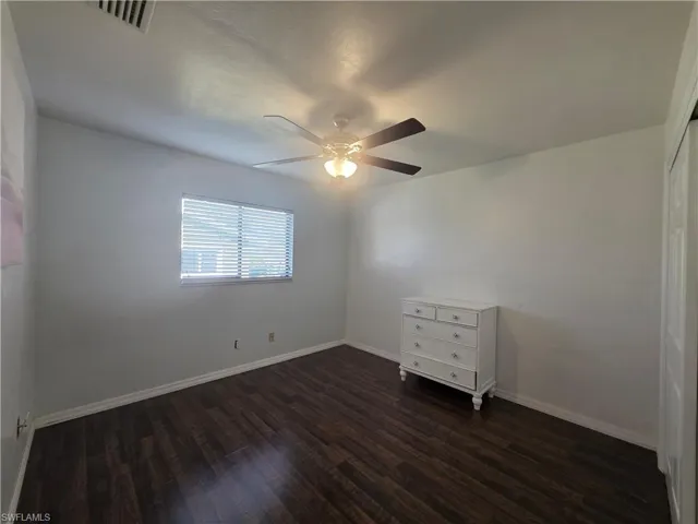 Unfurnished room with dark wood-type flooring and a ceiling fan