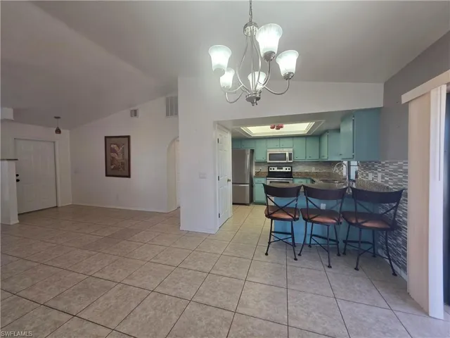 Kitchen with a breakfast bar area, dark countertops, vaulted ceiling, appliances with stainless steel finishes, and pendant lighting