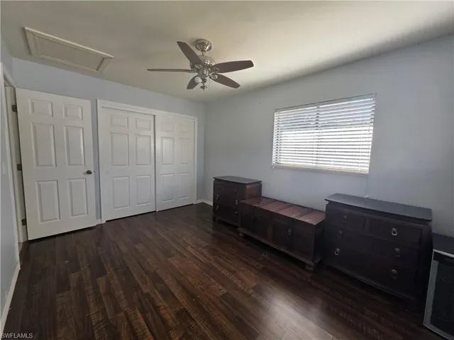 Bedroom with a closet, dark wood finished floors, a ceiling fan, and attic access