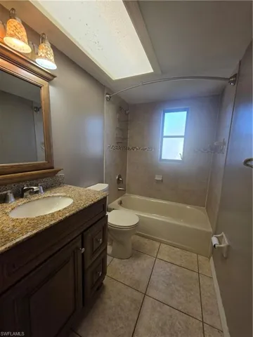 Bathroom with vanity, tub / shower combination, and light tile patterned flooring