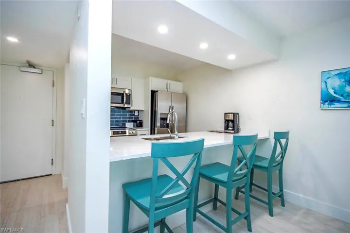 Kitchen with appliances with stainless steel finishes, light wood-style floors, a peninsula, white cabinets, and a breakfast bar area