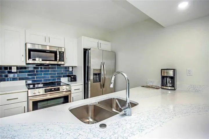 Kitchen with appliances with stainless steel finishes, white cabinets, backsplash, recessed lighting, and light stone countertops