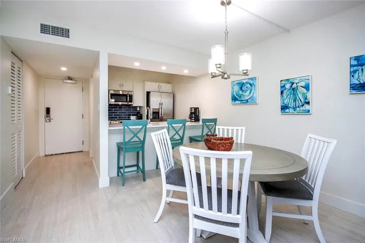 Dining area with light wood finished floors, a chandelier, and recessed lighting