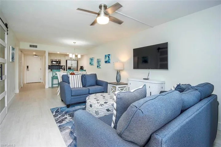 Living room featuring a chandelier, a ceiling fan, and a barn door