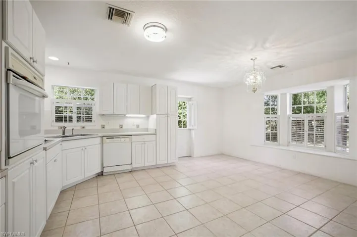 Kitchen with white cabinetry, white appliances, a chandelier, light countertops, and light tile patterned flooring