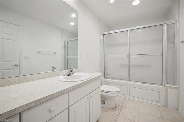 Bathroom featuring bath/shower combo with glass door, vanity, recessed lighting, and light tile patterned floors