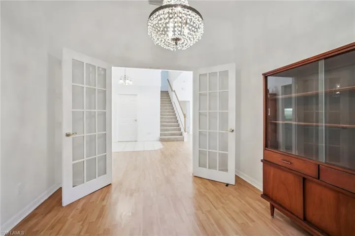 Sitting area featuring light wood laminate flooring, a chandelier, and French doors