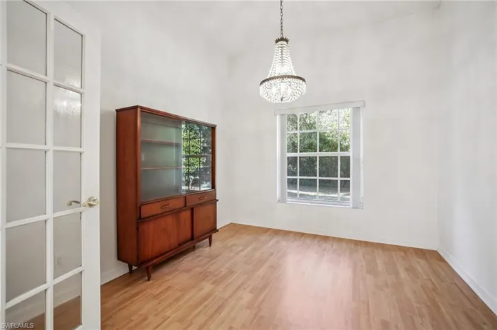 Other view of sitting area with suspended lighting, light wood laminate flooring, plenty of natural light, and a high ceiling