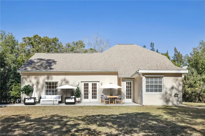 VIRTUALLY Staged Back of house with French doors, stucco siding, lawn, roof with shingles, and a patio
