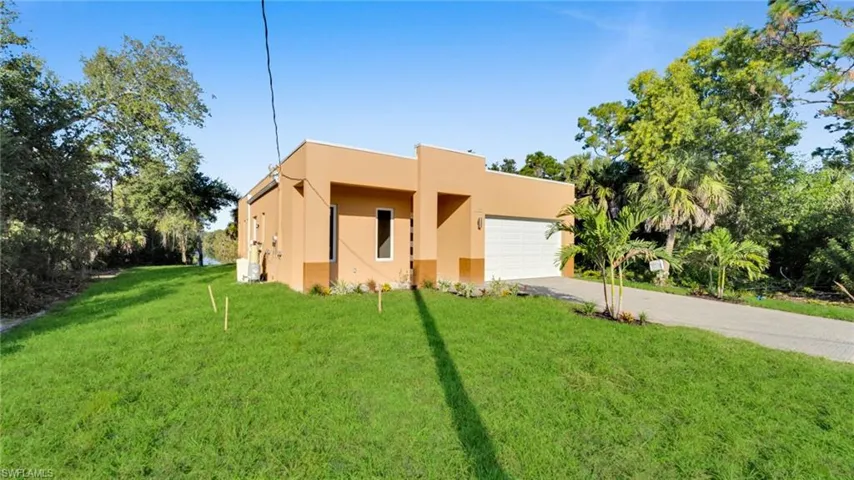View of front of home with a front yard, driveway, stucco siding, and a garage