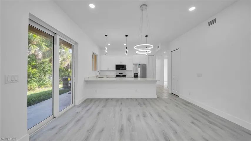 Kitchen featuring a peninsula, recessed lighting, light wood-style flooring, white cabinets, and stainless steel appliances