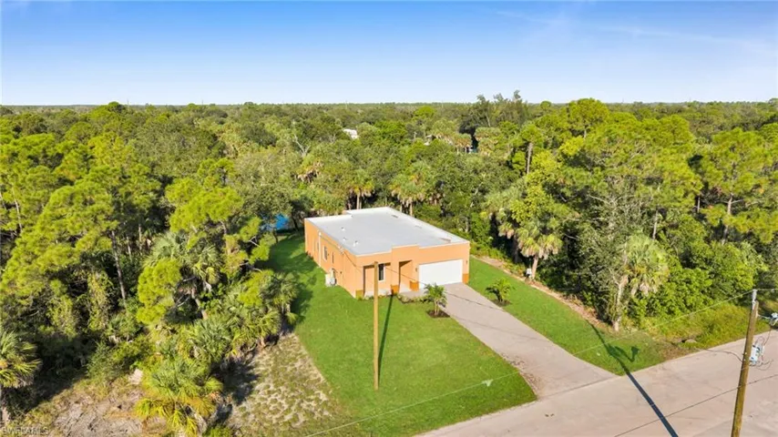 Aerial view of property and surrounding area featuring a forest