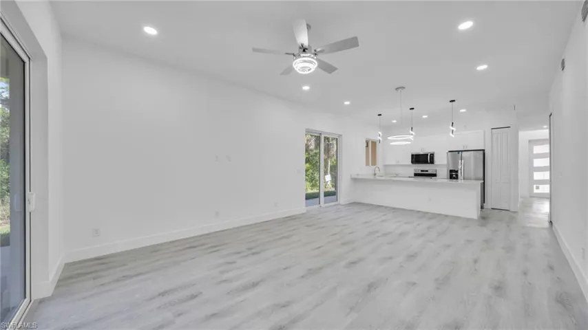 Unfurnished living room with plenty of natural light, light wood-type flooring, a ceiling fan, and recessed lighting
