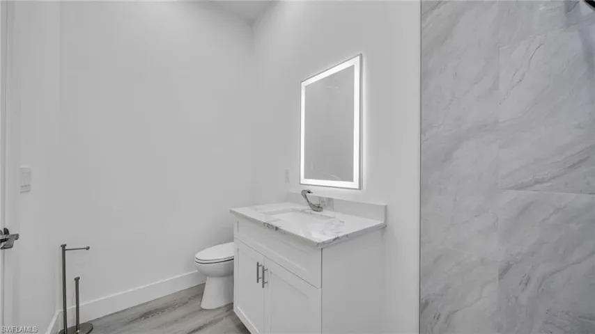 Bathroom with vanity, light wood-style floors, and a marble finish shower
