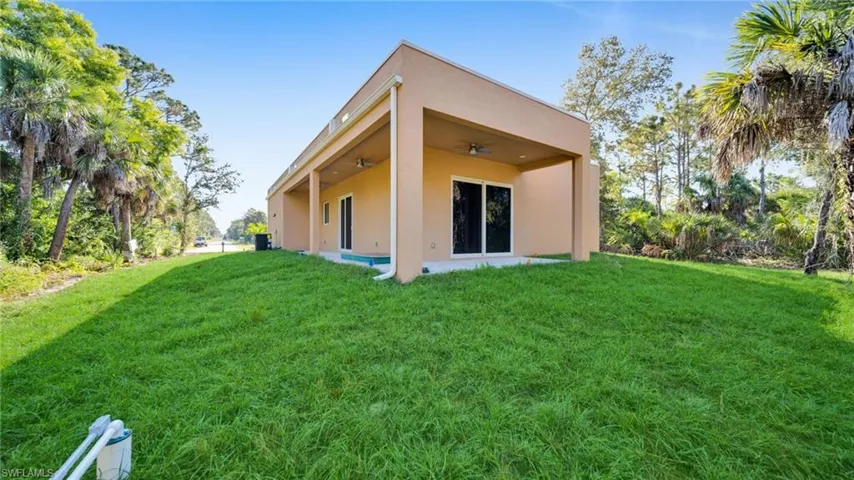 Back of property featuring a ceiling fan, a yard, stucco siding, and a patio