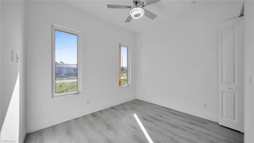 Empty room featuring plenty of natural light, light wood-type flooring, and ceiling fan