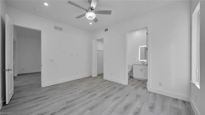 Unfurnished bedroom with light wood-style flooring, a spacious closet, recessed lighting, and a ceiling fan