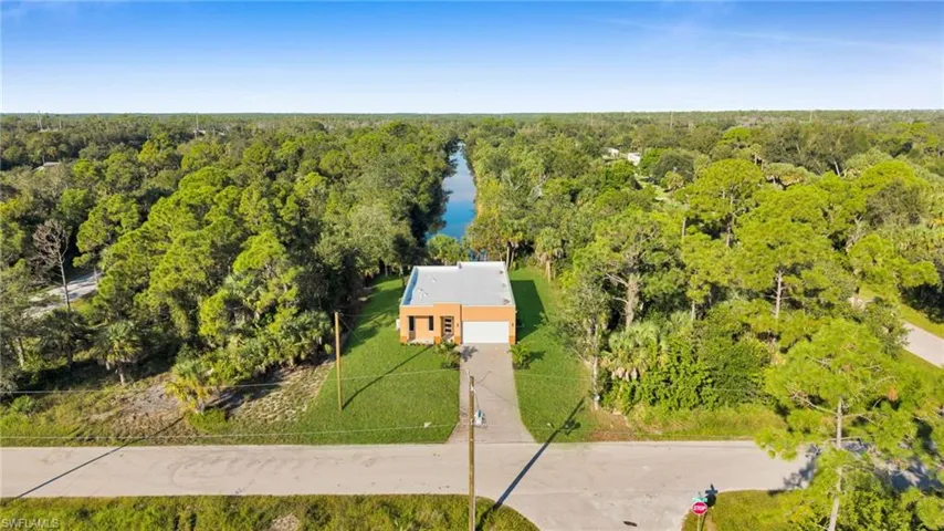View of subject property with a heavily wooded area and a nearby body of water