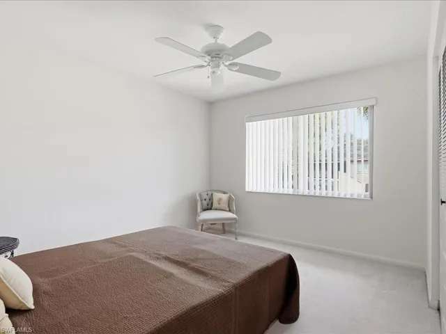 Carpeted bedroom with ceiling fan and baseboards