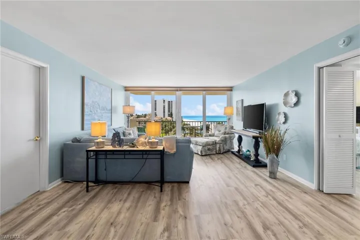 Living area featuring floor to ceiling windows, baseboards, and wood finished floors