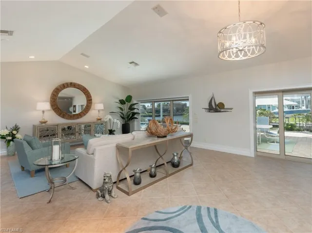 Living room featuring lofted ceiling, light tile patterned floors, and a notable chandelier