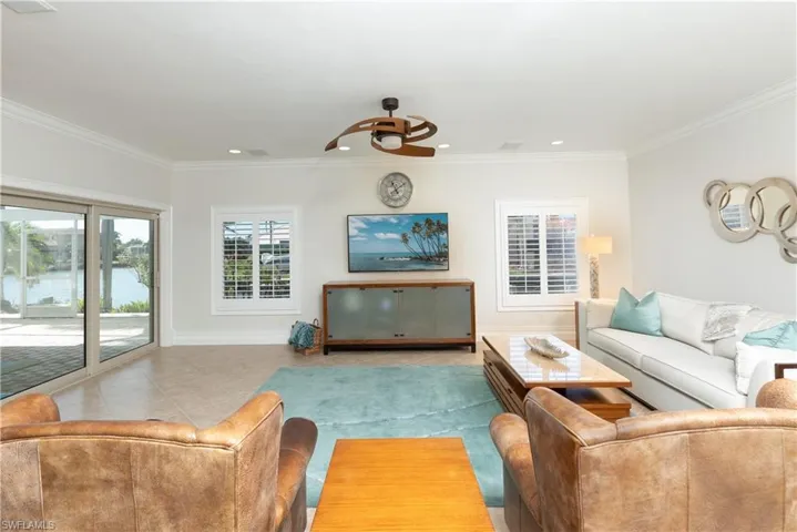 Living room featuring ceiling fan, tile patterned flooring, and ornamental molding