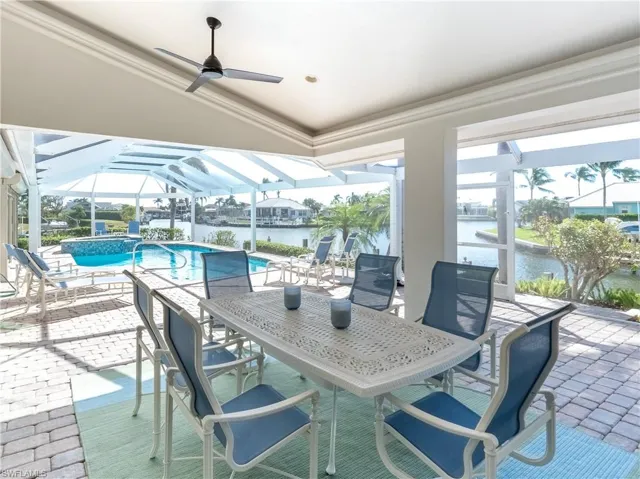 View of patio / terrace featuring ceiling fan, glass enclosure, and a water view