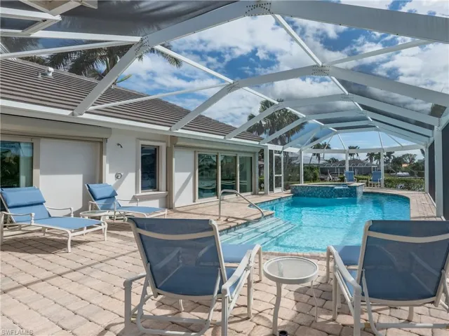 View of pool featuring a patio, glass enclosure, and an in ground hot tub
