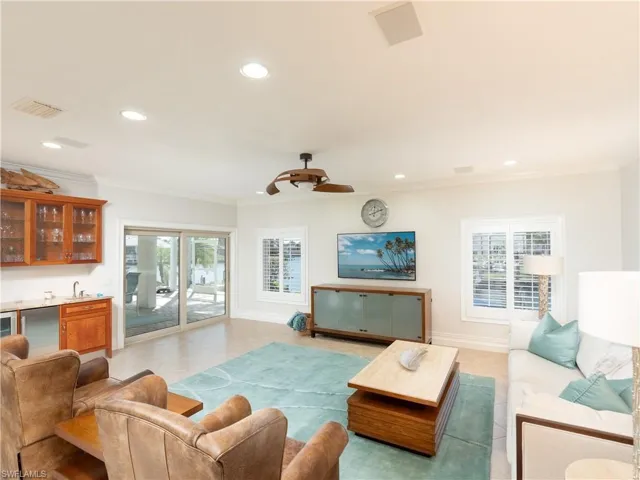 Living room featuring wet bar, a wealth of natural light, and crown molding