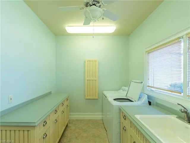Laundry room with light tile patterned floors, cabinets, sink, washing machine and dryer, and ceiling fan