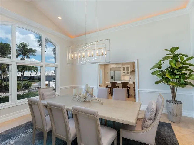 Tiled dining area featuring high vaulted ceiling, an inviting chandelier, and crown molding