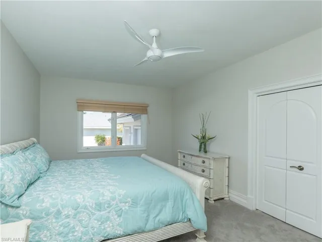 Carpeted bedroom with a closet and ceiling fan