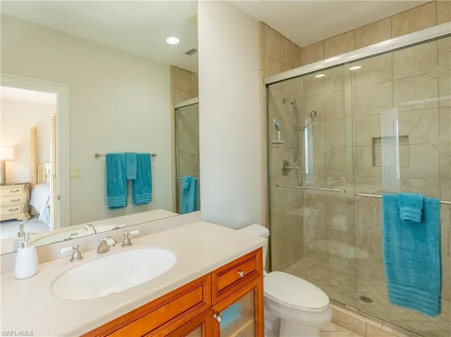 Bathroom featuring toilet, vanity, tile patterned flooring, and a shower with door