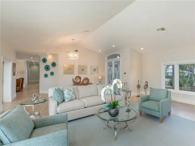 Living room with lofted ceiling, light tile patterned flooring, and an inviting chandelier