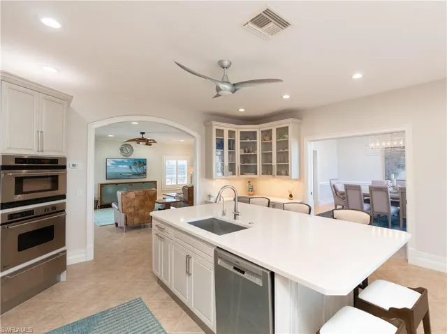 Kitchen with stainless steel appliances, sink, a kitchen bar, light tile patterned floors, and an island with sink
