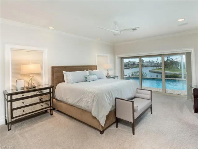 Carpeted bedroom with access to exterior, a water view, ceiling fan, and crown molding