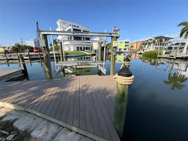 Waterfront property featuring a private boat dock with a lift system, composite decking, and direct canal access - Virtually Edited Image